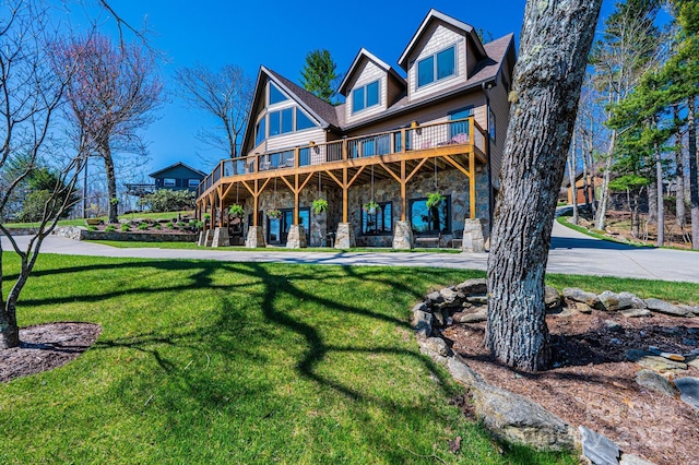 back of property featuring stone siding, a lawn, and a wooden deck