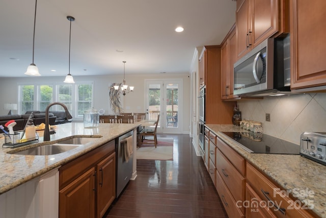kitchen with a sink, recessed lighting, backsplash, brown cabinets, and appliances with stainless steel finishes