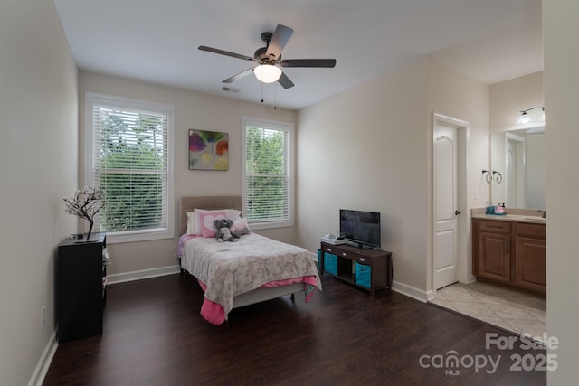 bedroom featuring wood finished floors, ceiling fan, baseboards, ensuite bath, and visible vents