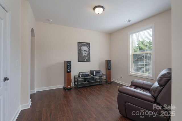 living area with visible vents, baseboards, arched walkways, and dark wood-style flooring