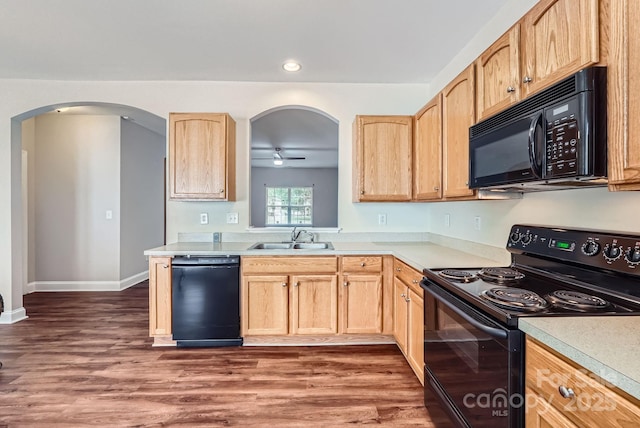 kitchen featuring black appliances, light brown cabinets, arched walkways, and a sink