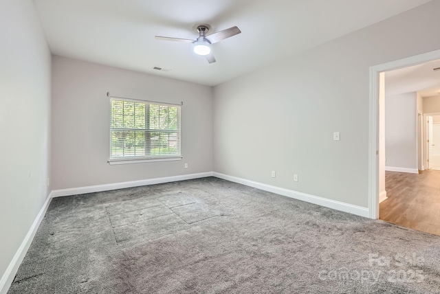carpeted empty room featuring baseboards, visible vents, and ceiling fan