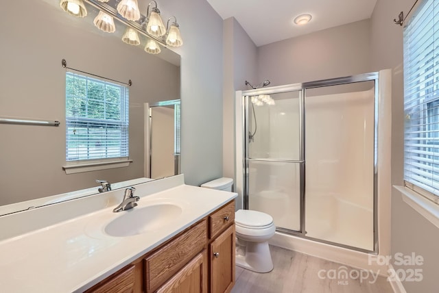 full bath with a stall shower, toilet, wood finished floors, and vanity