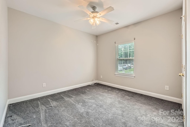 empty room featuring a ceiling fan, visible vents, dark colored carpet, and baseboards