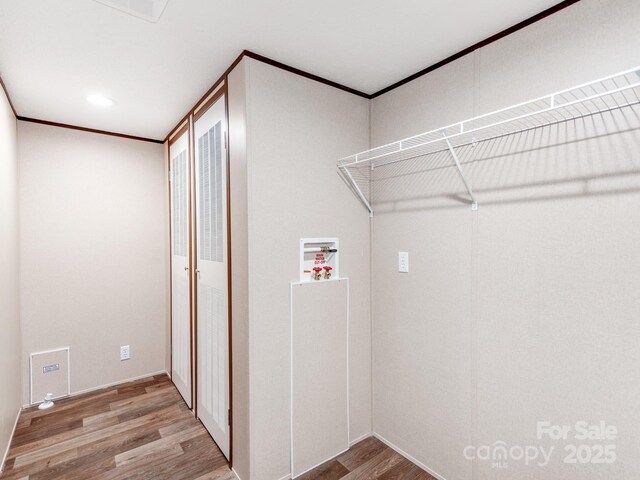 laundry area featuring washer hookup, wood finished floors, crown molding, and laundry area