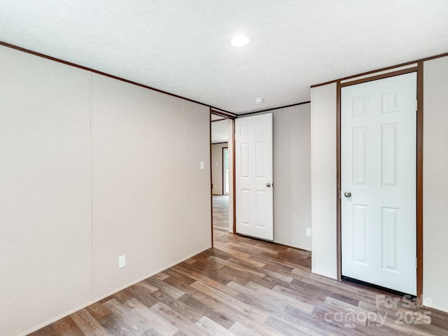 unfurnished bedroom featuring crown molding and light wood-style flooring