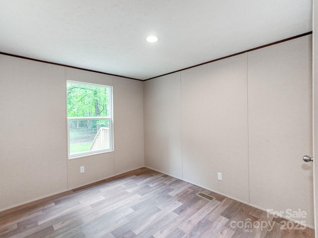 unfurnished room featuring recessed lighting, light wood-style floors, baseboards, and ornamental molding