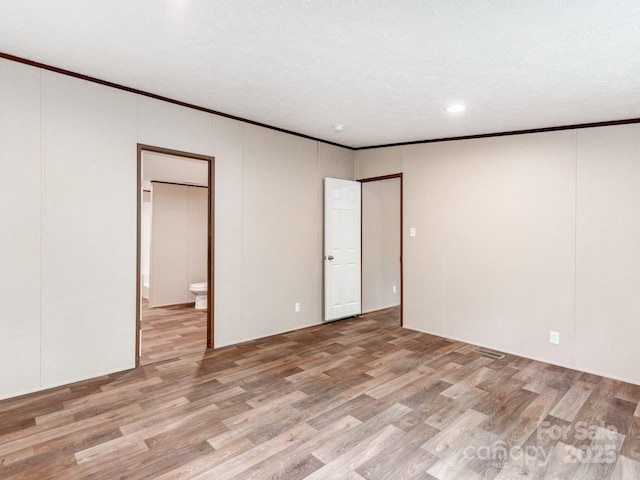 unfurnished bedroom with recessed lighting, light wood-type flooring, ornamental molding, and ensuite bathroom