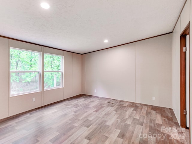 unfurnished room with a textured ceiling, recessed lighting, light wood-style floors, a decorative wall, and ornamental molding