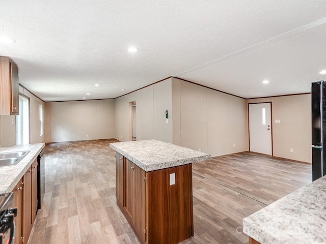 kitchen with light wood-style flooring, light countertops, a kitchen island, and brown cabinets