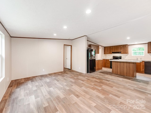 kitchen featuring light countertops, brown cabinetry, light wood finished floors, and black appliances