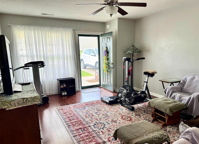 living area with hardwood / wood-style floors, a ceiling fan, visible vents, and a wealth of natural light