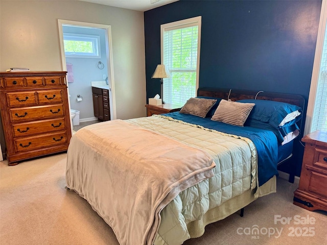 bedroom featuring ensuite bath and light colored carpet