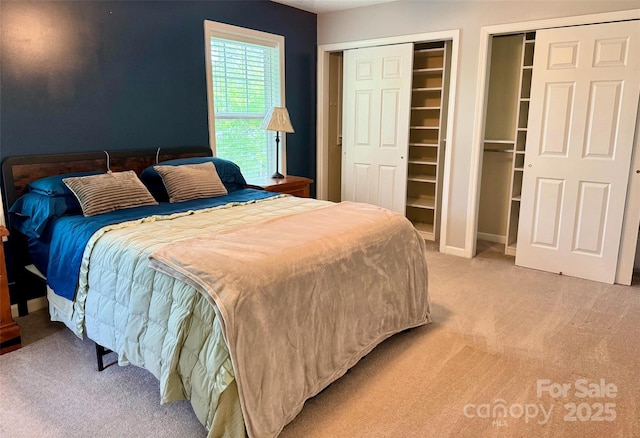 bedroom with light carpet and two closets
