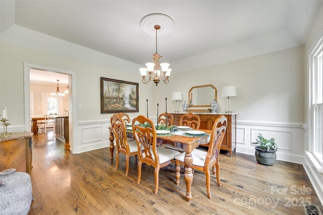 dining space featuring a notable chandelier, plenty of natural light, and a decorative wall