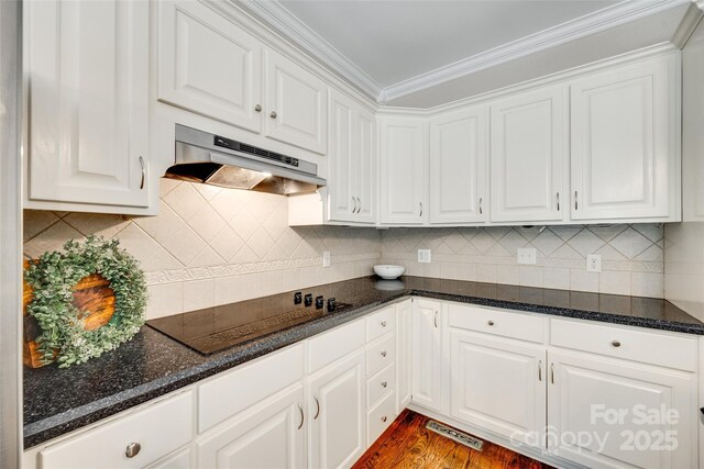 kitchen featuring ornamental molding, dark wood-style flooring, black electric stovetop, under cabinet range hood, and white cabinets