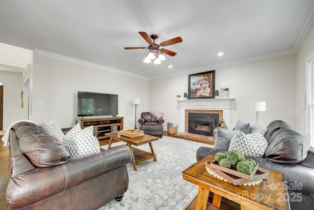 living room with crown molding, a brick fireplace, ceiling fan, and wood finished floors