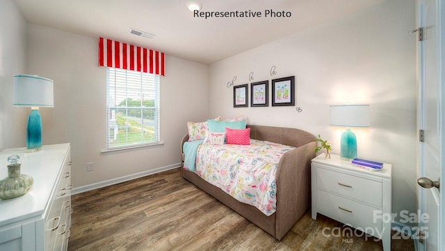 bedroom with visible vents, baseboards, and wood finished floors