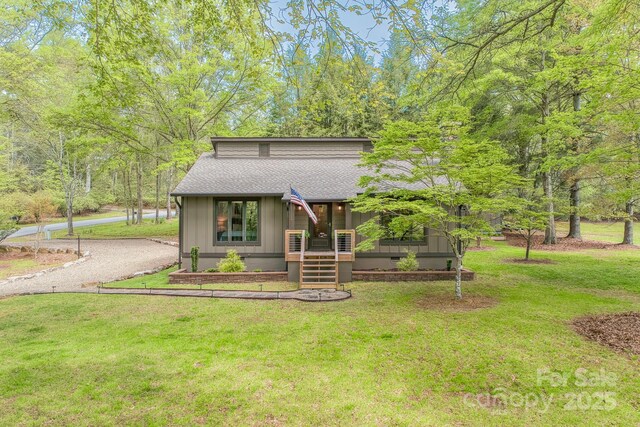 chalet / cabin featuring roof with shingles and a front lawn