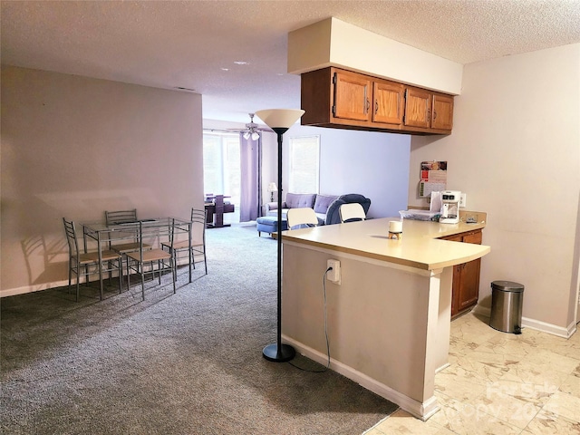 6234 Rosecroft Dr, Charlotte, NC 28215 - kitchen with a textured ceiling, brown cabinets, light countertops, baseboards, and a peninsula