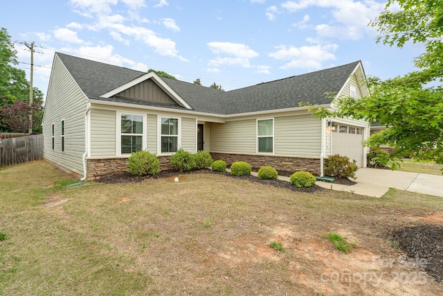 view of front facade featuring a shingled roof, a garage, driveway, stone siding, and fence