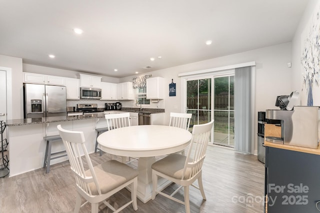 dining space with light wood-type flooring and recessed lighting