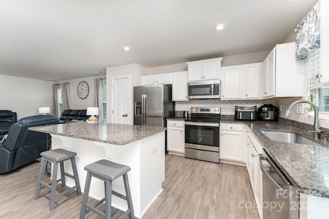 kitchen featuring light wood-style floors, open floor plan, appliances with stainless steel finishes, and a sink