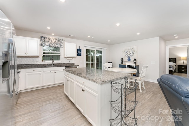 kitchen with a sink, stainless steel appliances, a kitchen bar, tasteful backsplash, and a kitchen island