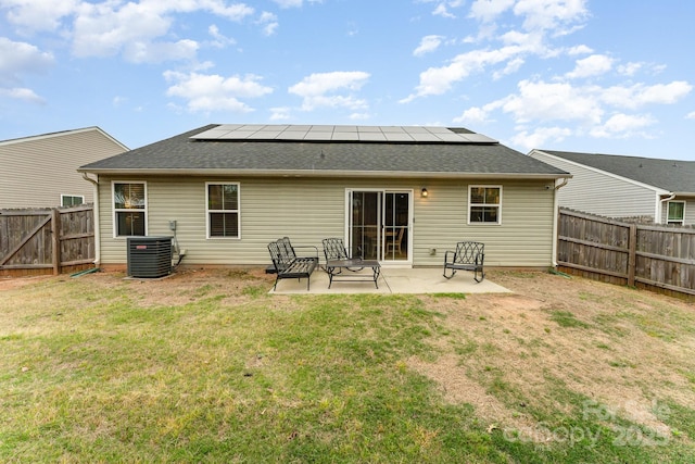 rear view of house with roof mounted solar panels, a patio, a yard, central AC unit, and a fenced backyard