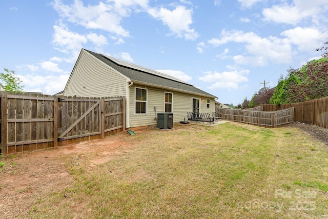 rear view of house with a lawn, a gate, central air condition unit, and a fenced backyard