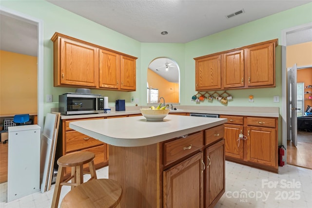 11913 Little Stoney Ct, Charlotte, NC 28269 - kitchen with a kitchen island, visible vents, light countertops, stainless steel microwave, and light floors