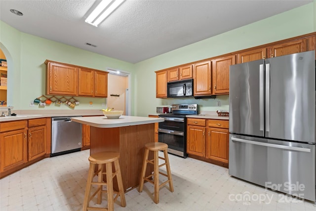 11913 Little Stoney Ct, Charlotte, NC 28269 - kitchen with light floors, a center island, light countertops, arched walkways, and stainless steel appliances