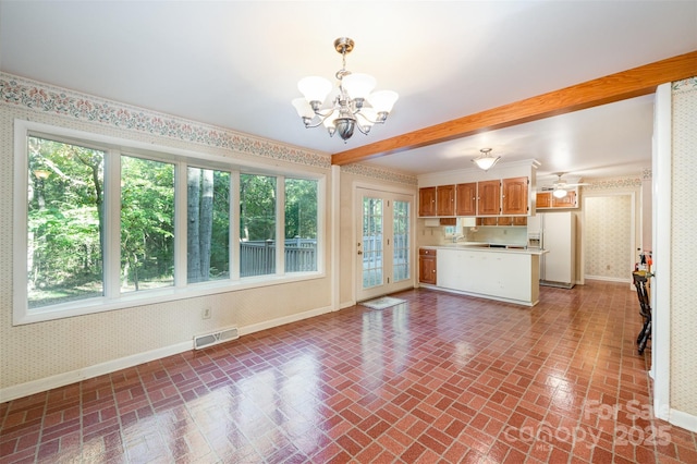 2643 Rolling Hills Dr, Monroe, NC 28110 - unfurnished living room with plenty of natural light, visible vents, a chandelier, wallpapered walls, and brick patterned floor