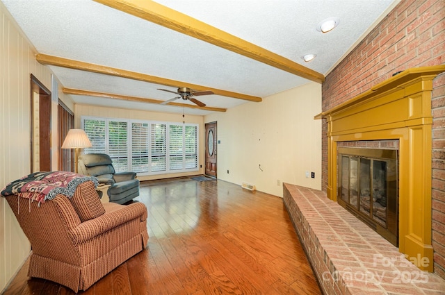 2643 Rolling Hills Dr, Monroe, NC 28110 - living area featuring a ceiling fan, wood finished floors, a textured ceiling, beamed ceiling, and a brick fireplace