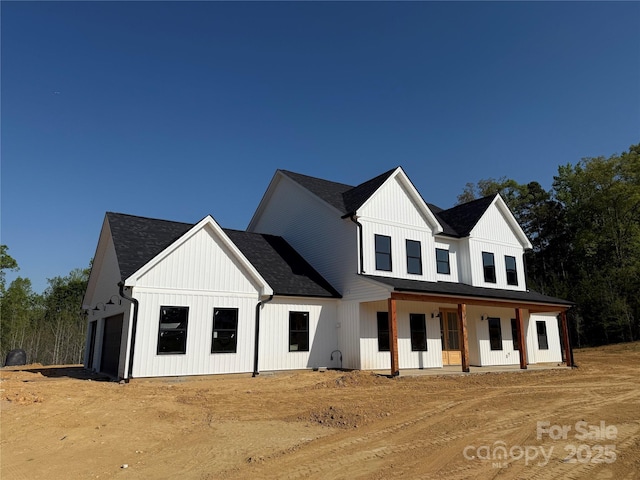 view of front of property featuring board and batten siding, a shingled roof, covered porch, and a garage