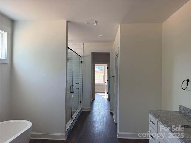 full bath with a freestanding bath, wood finished floors, vanity, baseboards, and a stall shower