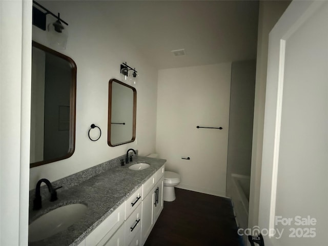 bathroom with a bathtub, a sink, double vanity, and toilet