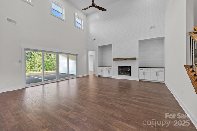 4034 Daugherty Rd, China Grove, NC 28023 - unfurnished living room featuring a towering ceiling, ceiling fan, dark wood-style flooring, and a fireplace