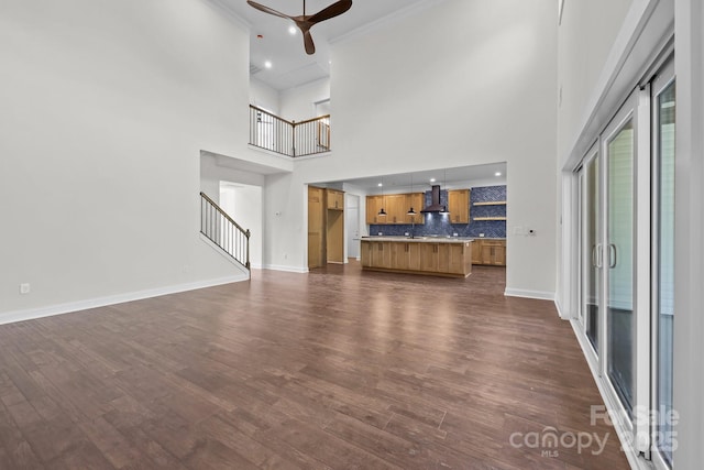 4034 Daugherty Rd, China Grove, NC 28023 - unfurnished living room featuring ceiling fan, a towering ceiling, dark wood-type flooring, stairway, and crown molding