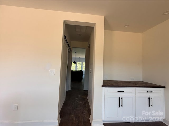 hall featuring baseboards, dark wood-style flooring, and recessed lighting