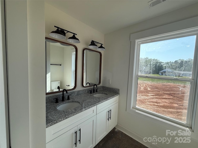 bathroom with visible vents, a sink, double vanity, and toilet