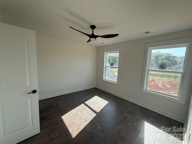 spare room with dark wood-style floors, baseboards, a ceiling fan, and visible vents