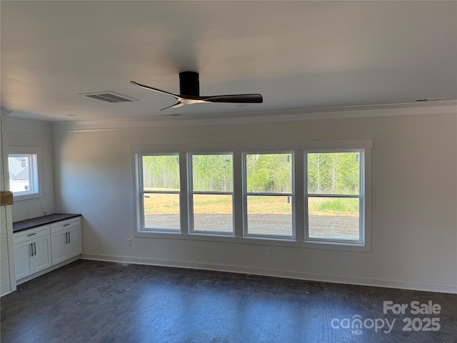 unfurnished room with a ceiling fan, dark wood finished floors, baseboards, ornamental molding, and visible vents