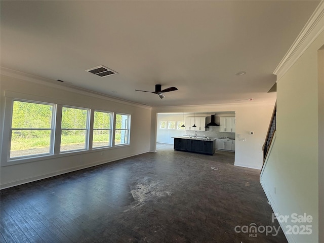 unfurnished living room featuring ceiling fan, visible vents, baseboards, and ornamental molding