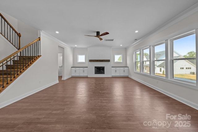 4040 Daugherty Rd, China Grove, NC 28023 - unfurnished living room featuring a ceiling fan, healthy amount of natural light, dark wood-style floors, ornamental molding, and a large fireplace
