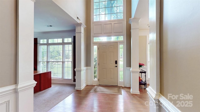 entrance foyer with plenty of natural light, visible vents, ornate columns, and wood finished floors