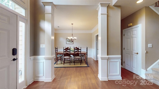 foyer with wood finished floors, ornate columns, and an inviting chandelier