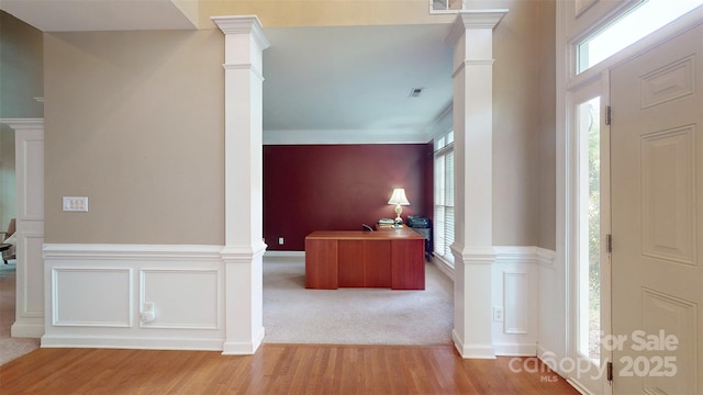entrance foyer featuring wainscoting, wood finished floors, and ornate columns