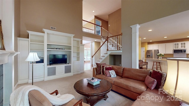 living room featuring recessed lighting, ornate columns, light colored carpet, a high ceiling, and stairs