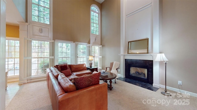 carpeted living room featuring a fireplace, a wealth of natural light, and a towering ceiling